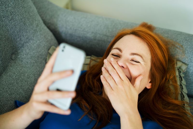 Eine Frau kichert, während sie ein Telefon liest.