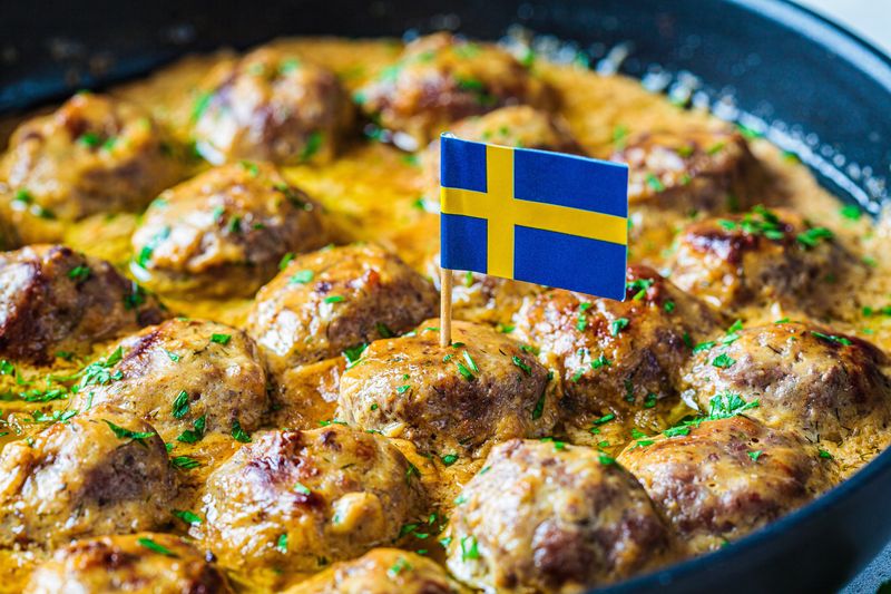 Schwedische Fleischbällchen in cremiger Sauce in einer schwarzen Pfanne, grauer Hintergrund, Nahaufnahme. Skandinavisch ...