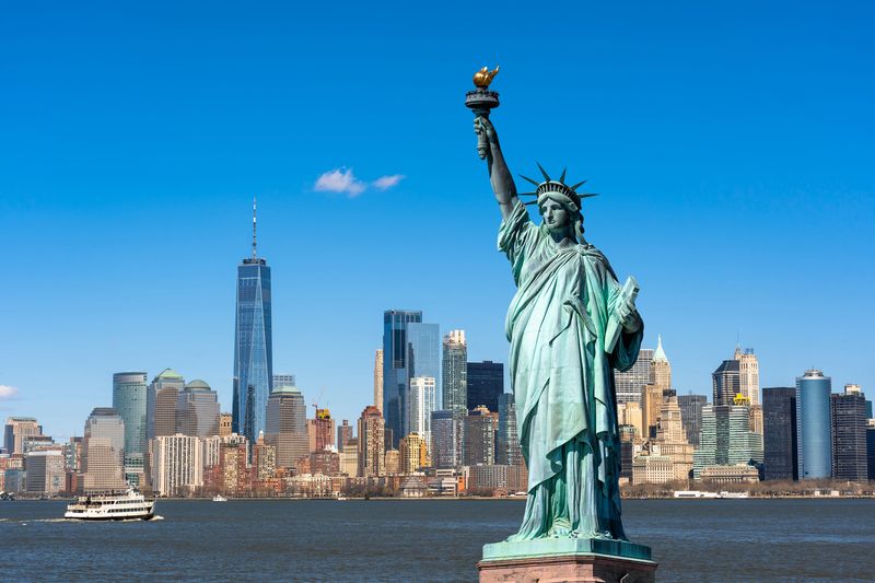 Die Freiheitsstatue über der Szene des New Yorker Stadtbildes am Flussufer, deren Standort Lower Manhattan ist ...