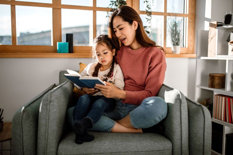 Eine junge Mutter bringt ihrem Kind das Lesen bei.