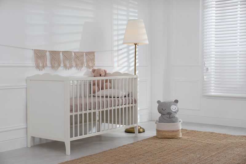 Niedliches Babyzimmer mit bequemer Krippe und Teddybär