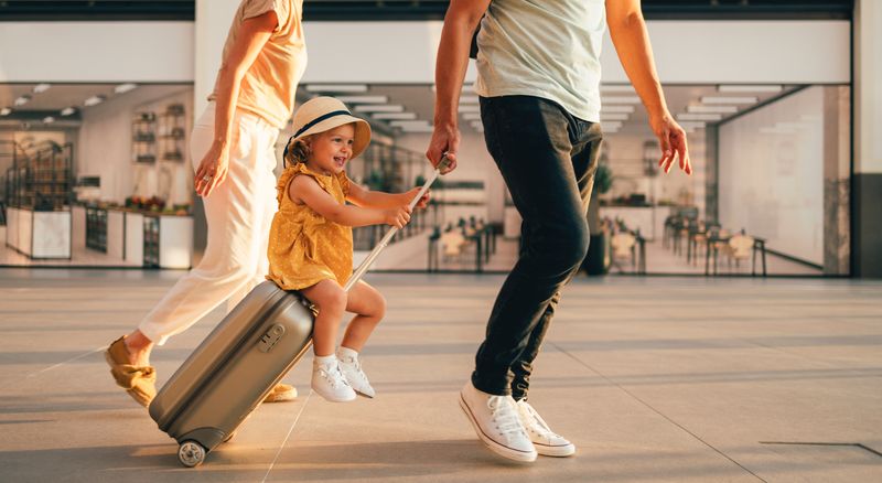 Ein kleines Mädchen schlendert mit ihren Eltern durch den Flughafen.